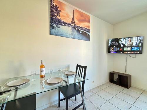 a dining room with a table with two chairs and a tv at Vaillant - Tout confort - Fibre - 5min du Tramway #SirDest in Bezons