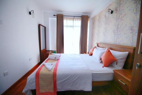 a bedroom with a bed with orange and white pillows at Nelma's Cosy in Nuwara Eliya