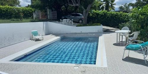a swimming pool with chairs and a table and a table and chairs at Casa verde, Rancho de los Caballeros in Tocaima