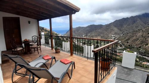 a balcony with chairs and a view of the mountains at Casa La Sabina Roja 1 - Casa con impresionantes vistas sobre Hermigua y el mar in Hermigua