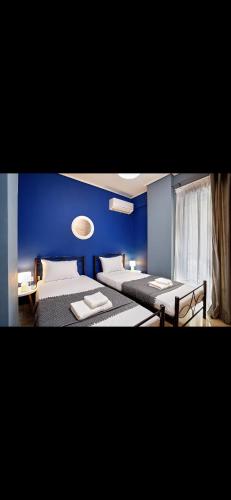 1 dormitorio con 2 camas y pared azul en Cozy apartment next to the port!, en Pireo