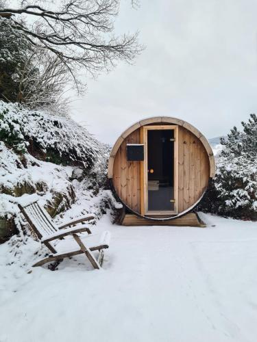 a wooden cabin with a bench in the snow at Chalet Spessart in Dammbach