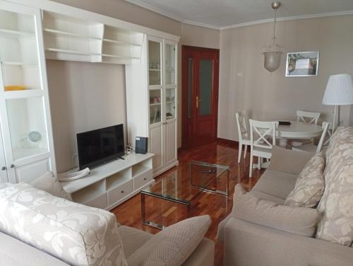 sala de estar con sofá, TV y mesa en Centro-GASCONA con terraza, garaje y wifi gratuito en Oviedo