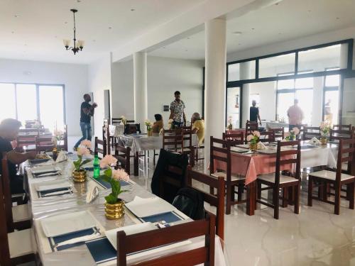 a dining room with tables and people standing in the background at Edificio Cosec Hotel in Cova Figueira