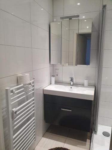 a white bathroom with a sink and a mirror at Ferienwohnung/Montagewohnung 2 in Bad Driburg