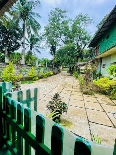 a fence in front of a house with a driveway at Jm Resort in Dambulla
