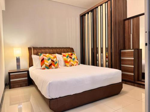 a bedroom with a large bed with two colorful pillows at 2BR Summer Suites @KLCC in Kuala Lumpur