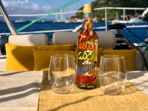 - une bouteille d'alcool assise sur une table avec deux verres à vin dans l'établissement Baradozig, à Terre-de-Haut