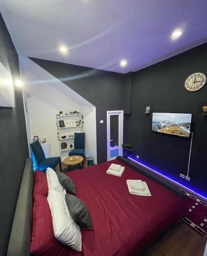 um quarto com uma cama vermelha e um relógio na parede em London.Apartments em Pristina