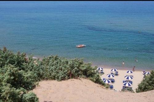 a beach with umbrellas and people in the water at Villa Dune di Scivu in Portixeddu