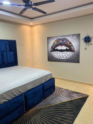 Magic City Apartments في Kasoa: غرفة نوم بسرير مع لوحة على الحائط