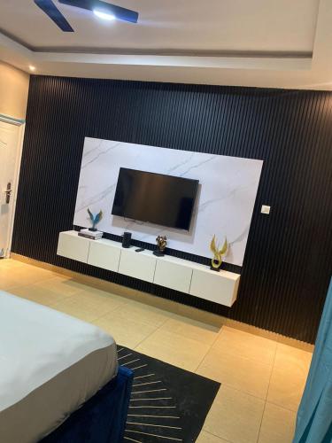 a bedroom with a large screen television on a wall at Magic City Apartments in Kasoa