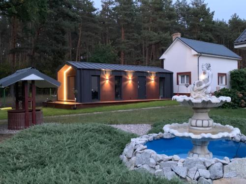 ein schwarzweißes Haus mit einem Brunnen im Hof in der Unterkunft Na Skraju Lasu Bielinek in Cedynia