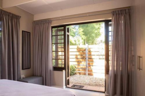 Un dormitorio con una cama y una gran puerta corrediza de vidrio. en Mill Park Garden Cottage, en Gqeberha