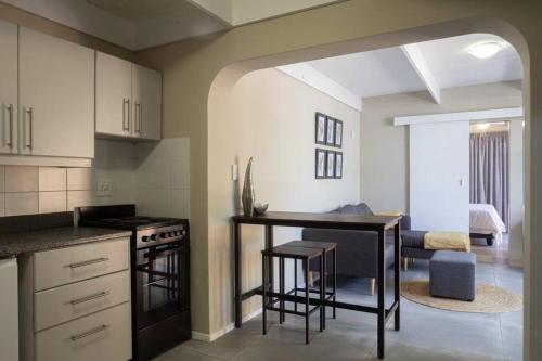 a kitchen with a counter and a table in a room at Mill Park Garden Cottage in Gqeberha