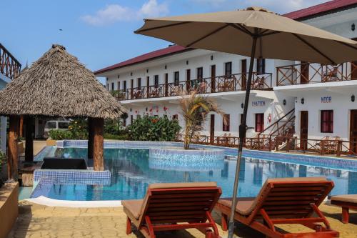 a resort with a swimming pool with two chairs and an umbrella at Canary Two & SPA in Nungwi