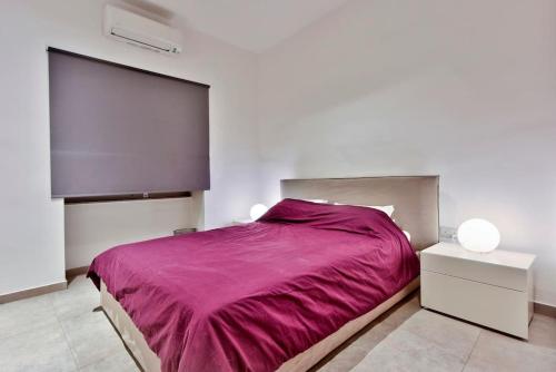a bedroom with a large bed with a purple blanket at Modern 3 BED & 2 BTH APT Sliema in Sliema