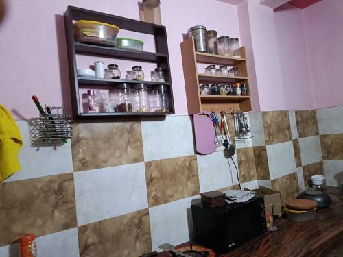 a kitchen with a tiled wall with a shelf with bottles at Beautiful Spacious 1 BHK in New Delhi