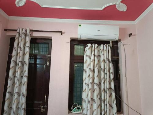 a room with two windows with curtains and a air conditioner at Beautiful Spacious 1 BHK in New Delhi
