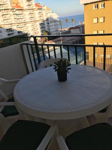 a white table with a potted plant on a balcony at peñiscola playa primera linea ,parquing incluido in Peñíscola