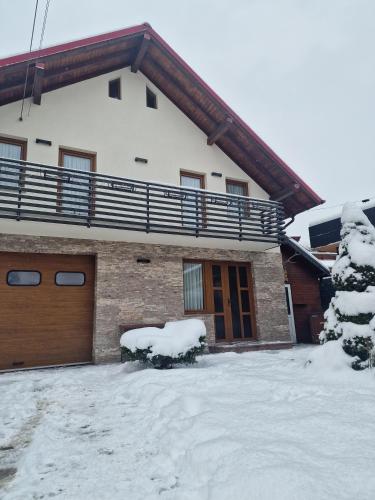 a house with snow on the ground in front of it at Comfy House in Borşa