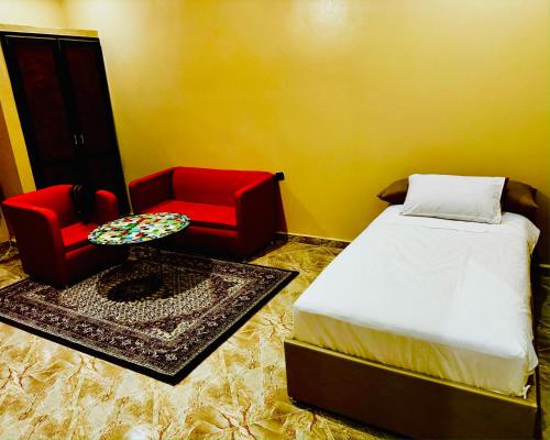a bedroom with a bed and two red chairs at COMPLEXE L'OASIS in Erfoud
