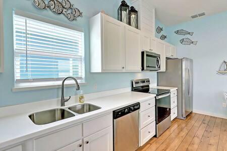 a kitchen with white cabinets and stainless steel appliances at Mary Lou's Hideout (11th St Bungalows #19) in Port Aransas