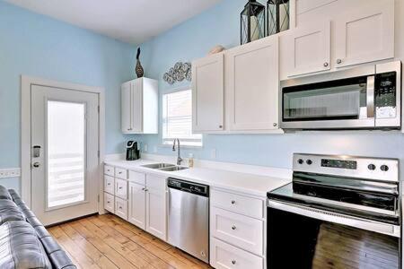 a kitchen with white cabinets and a stove top oven at Mary Lou's Hideout (11th St Bungalows #19) in Port Aransas