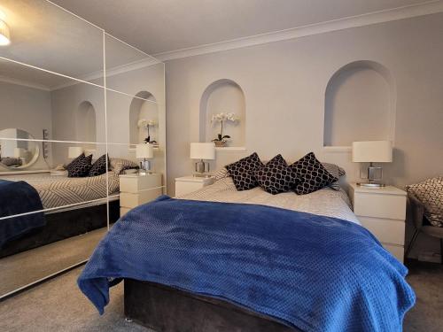 a bedroom with a bed with a blue blanket and mirrors at 39 Queens Road in Swanage