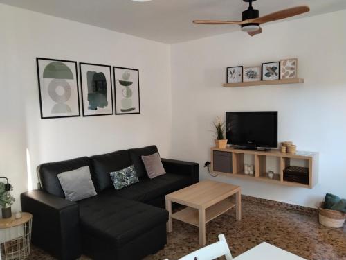 a living room with a black couch and a tv at La fuente in Güéjar-Sierra