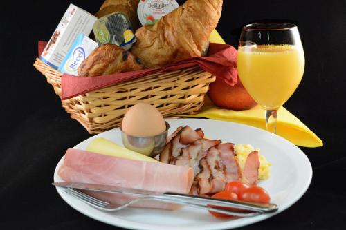 a plate of food with a basket of bread and a glass of orange juice at Hotel Restaurant Piccard in Vlissingen