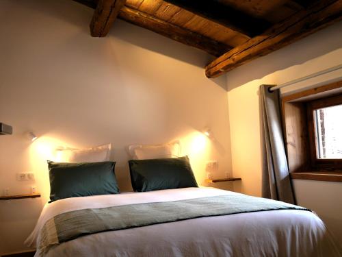 a bedroom with a large bed with two green pillows at La ferme d'Hauteluce - Chalets in Hauteluce