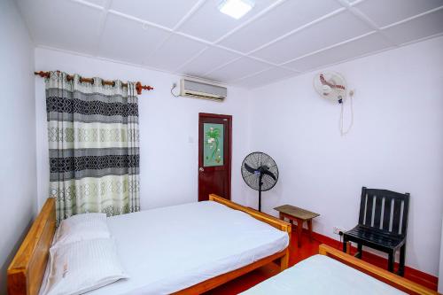 a bedroom with a bed and a chair and a fan at Villa Ravichini in Polonnaruwa