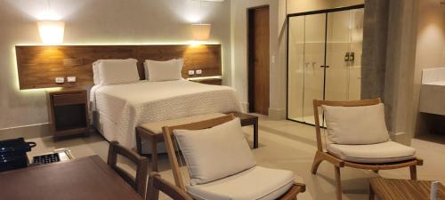 a hotel room with a bed and two chairs at Hiu Hotel in Juquei