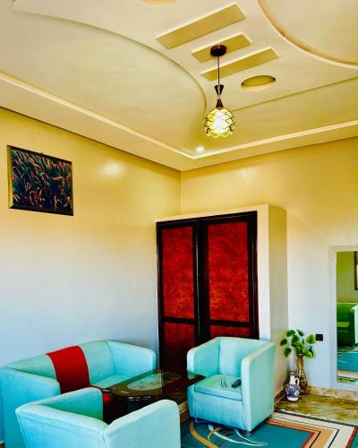 a living room with blue chairs and a table at COMPLEXE L'OASIS in Erfoud