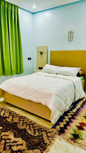 a bedroom with a large bed with a green curtain at COMPLEXE L'OASIS in Erfoud