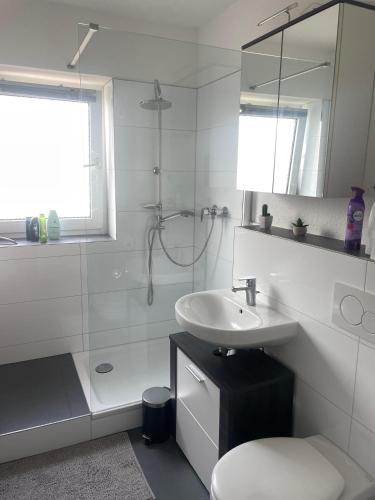 een witte badkamer met een wastafel en een douche bij Messe/EventApartment in Hannover