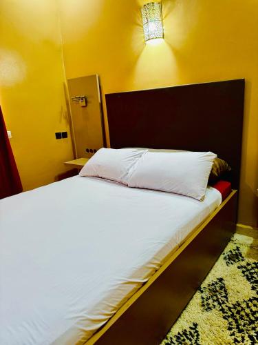 a bedroom with a white bed with a black headboard at COMPLEXE L'OASIS in Erfoud