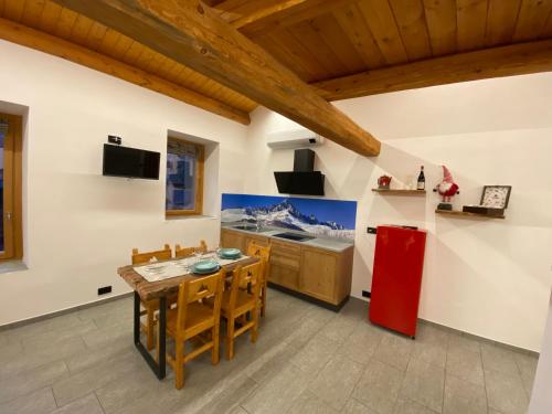 una cucina con tavolo e frigorifero rosso di BAITA GHITIN a Ostana