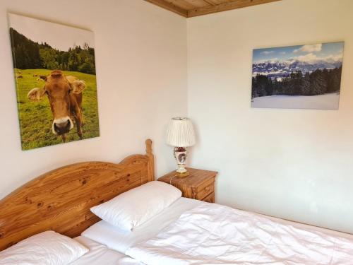 una camera con letto e una foto di una mucca sul muro di Ferienwohnung im kuhlen Allgäu a Missen-Wilhams