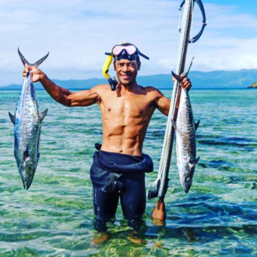 a man holding two fish in the water at Private Oceanfront Fijian Villa Sleeps 8 in Malolo