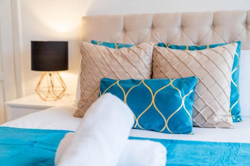 1 dormitorio con 1 cama con almohadas azules y blancas en 4 Bed House - Lots of Parking - Garden - Fast WIFI - Groups - Contractors - Excelled Value Accommodation - 802W, en Birmingham