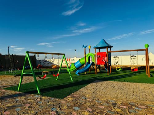 un parque infantil con tobogán y columpio en COMPLEXE L'OASIS en Erfoud