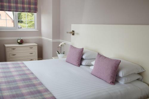 a bedroom with a white bed with purple pillows at Badgers Mount Hotel in Earl Shilton