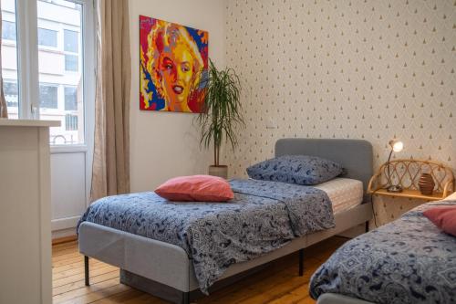 a bedroom with two beds and a painting on the wall at Plumeria - Grand Appartement 75m2 - Au calme avec Jardin - Idéal Famille ou Groupe de Travailleurs - Parking Public Gratuit - 2 Chambres - 4 Lits séparés in Metz