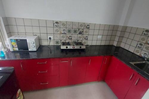 una pequeña cocina con armarios rojos y microondas en Entire 1 BHK Cottage en Nainital