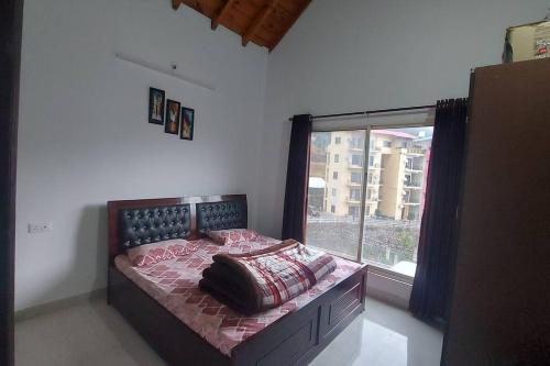 a bedroom with a bed with a large window at Entire 1 BHK Cottage in Nainital