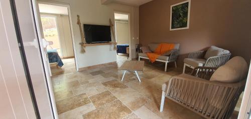 a living room with a couch and a tv at Résidence Belle Anse Trois-ilets in Les Trois-Îlets