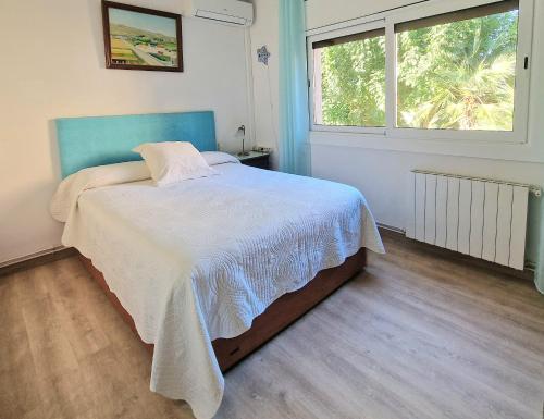 a bedroom with a bed with a blue headboard and a window at Pool and relax 20' from Barcelona in Premiá de Mar