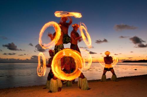 a group of people standing on the beach with a fire sculpture at Private Oceanfront Fijian Villa Sleeps 8 in Malolo